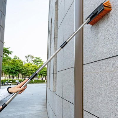 homme nettoie mur balai extérieur