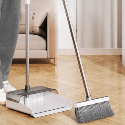 homme nettoie salon Pelle et balayette manche long