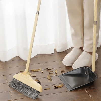 femme nettoie saleté au salon avec balai pelle bois acier
