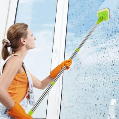 femme lave fenêtre avec brosse télescopique vert