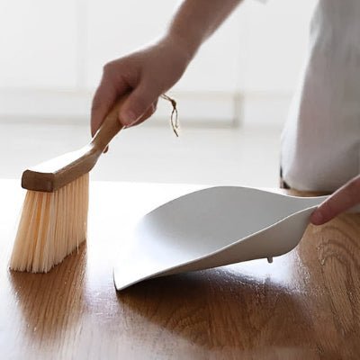 elle nettoie table avec pelle et balayette