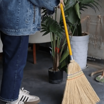 femme balaye à l'intérieur de sa maison avec balai en paille