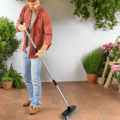 homme nettoie terrasse balai extérieur